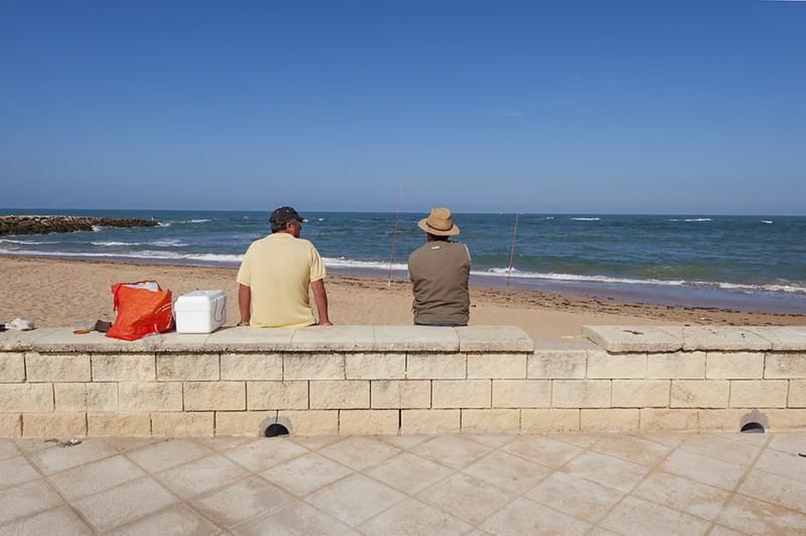 Dos hombres disfrutando de una jornada de pesca en una de las playas de Chipiona Dos hombres disfrutando de una jornada de pesca en una de las playas de Chipiona