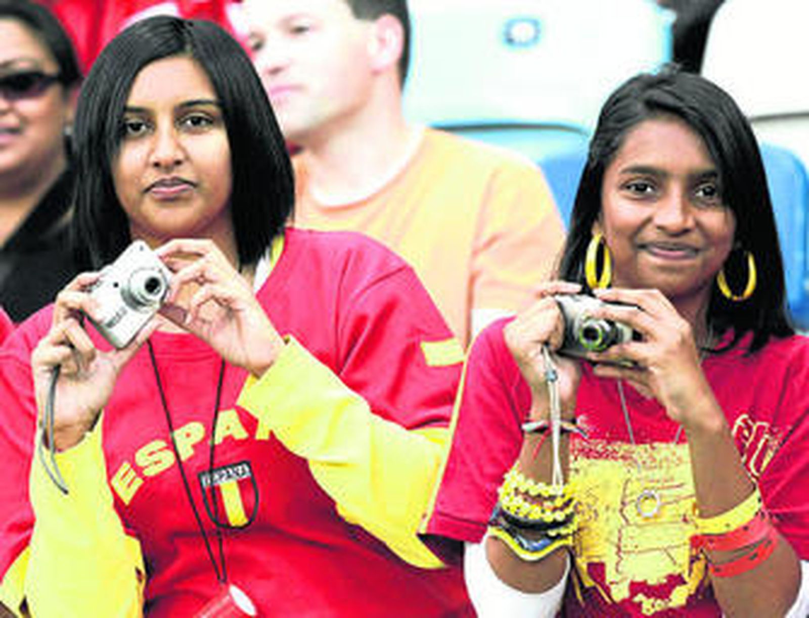 1. Dos aficionadas de origen hindú, que no fueron las únicas, acudieron al partido ataviadas con ropa de la selección española, a la que apoyaron. 2. Los Príncipes de Asturias, como hicieron hace cuatro años en el Mundial de Alemania, acudieron al primer partido de la selección española, que vieron desde el palco de autoridades. 3. Varios aficionados españoles reaccionan ante una jugada del partido en la zona habilitada junto al estadio Santiago Bernabéu, donde se ubicaron dos pantallas gigantes. 4. Hinchas helvéticos muestran en la grada unos carteles en los que se lee "El chocolate derrota a la paella", un titular que tira de tópicos.