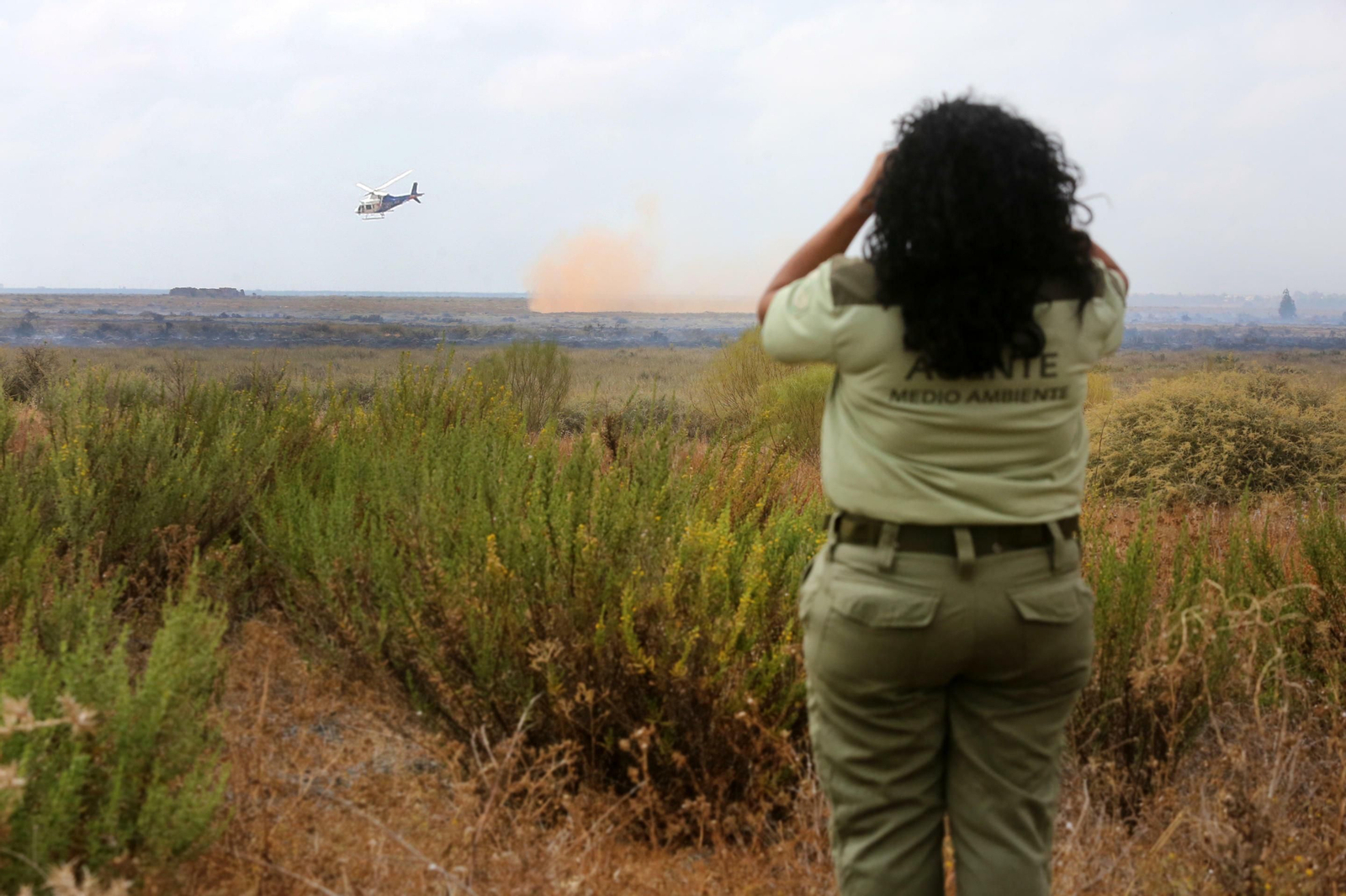 Un agente de Medio Ambiente observa el incendio que sobrevuela un helicoptero.