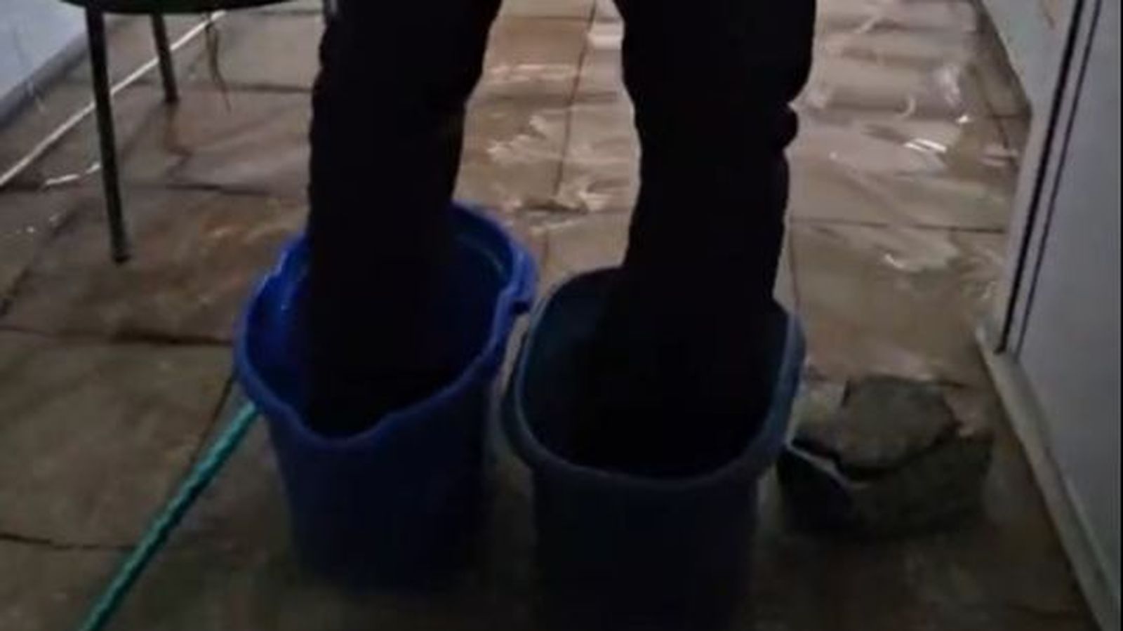 Un agente, rodeado de agua y con los pies en cubos dentro de la comisaría.