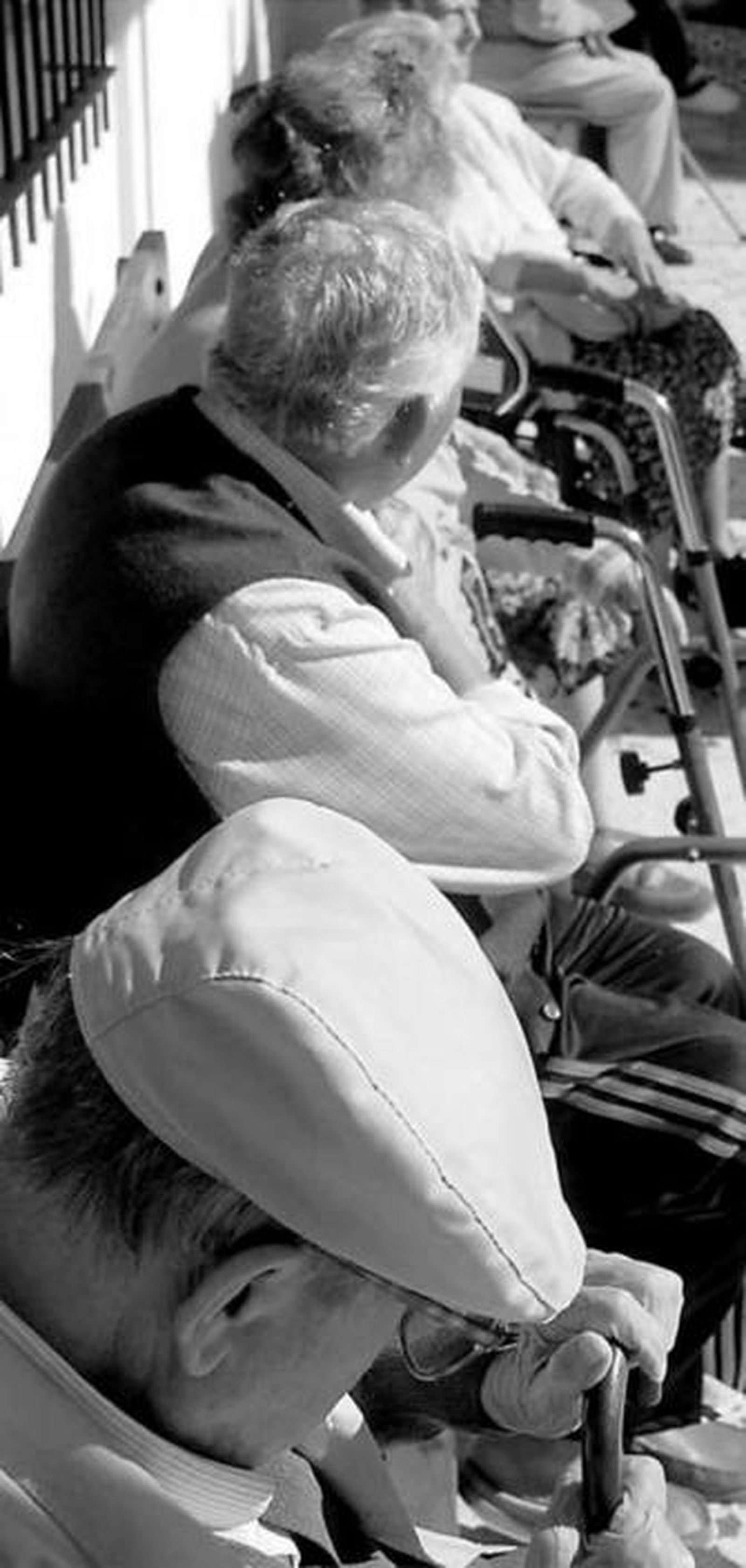 Varios mayores descansan sentados al sol.