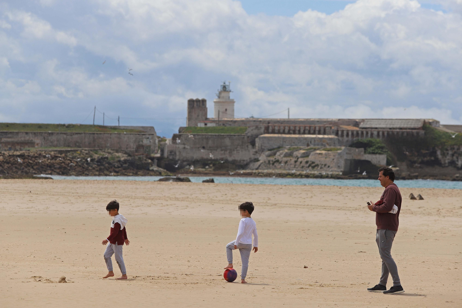 Dos niños juegan junto a su padre, este martes en Tarifa.