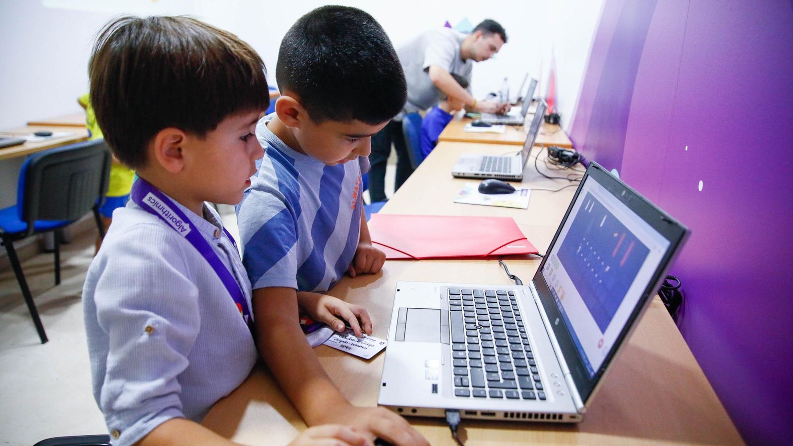 Dos pequeños ayudándose entre ellos en la clase de programación.