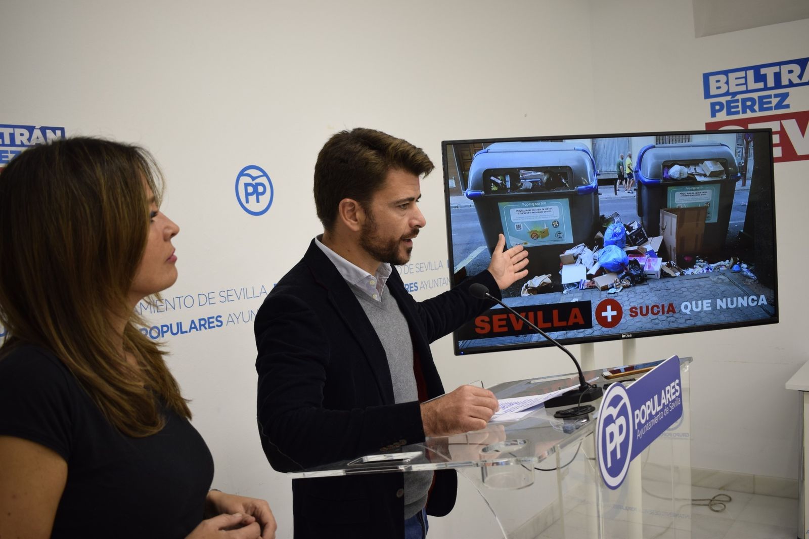 El portavoz del PP, Beltrán Pérez, muestra una imagen del estado de los contendores en rueda de prensa.