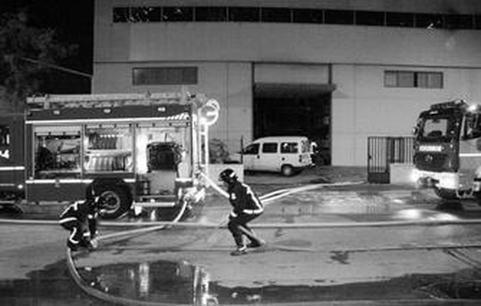 Dos bomberos, en plena tarea de extinción del fuego cerca de la medianoche.