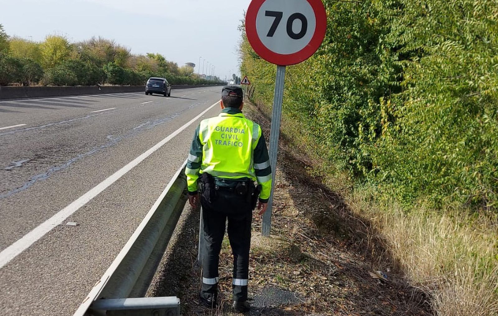 Un agente de la Guardia Civil frente a una señal de tráfico.
