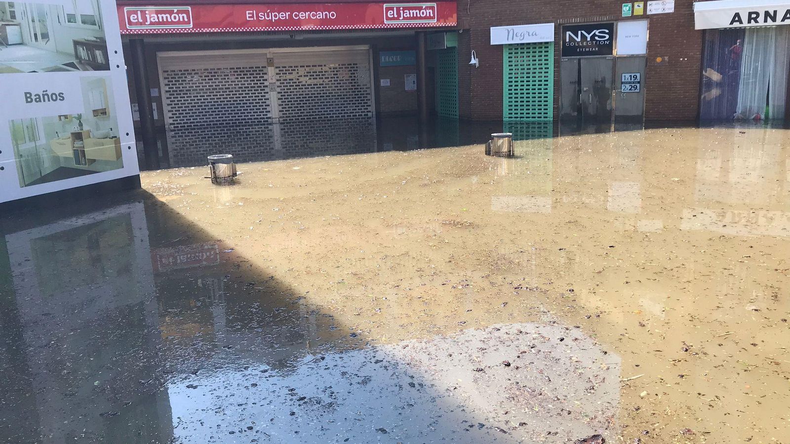 Al menos medio metro de agua y barro en el patio central del centro comercial de Islantilla, a la entrada de El Jamón.