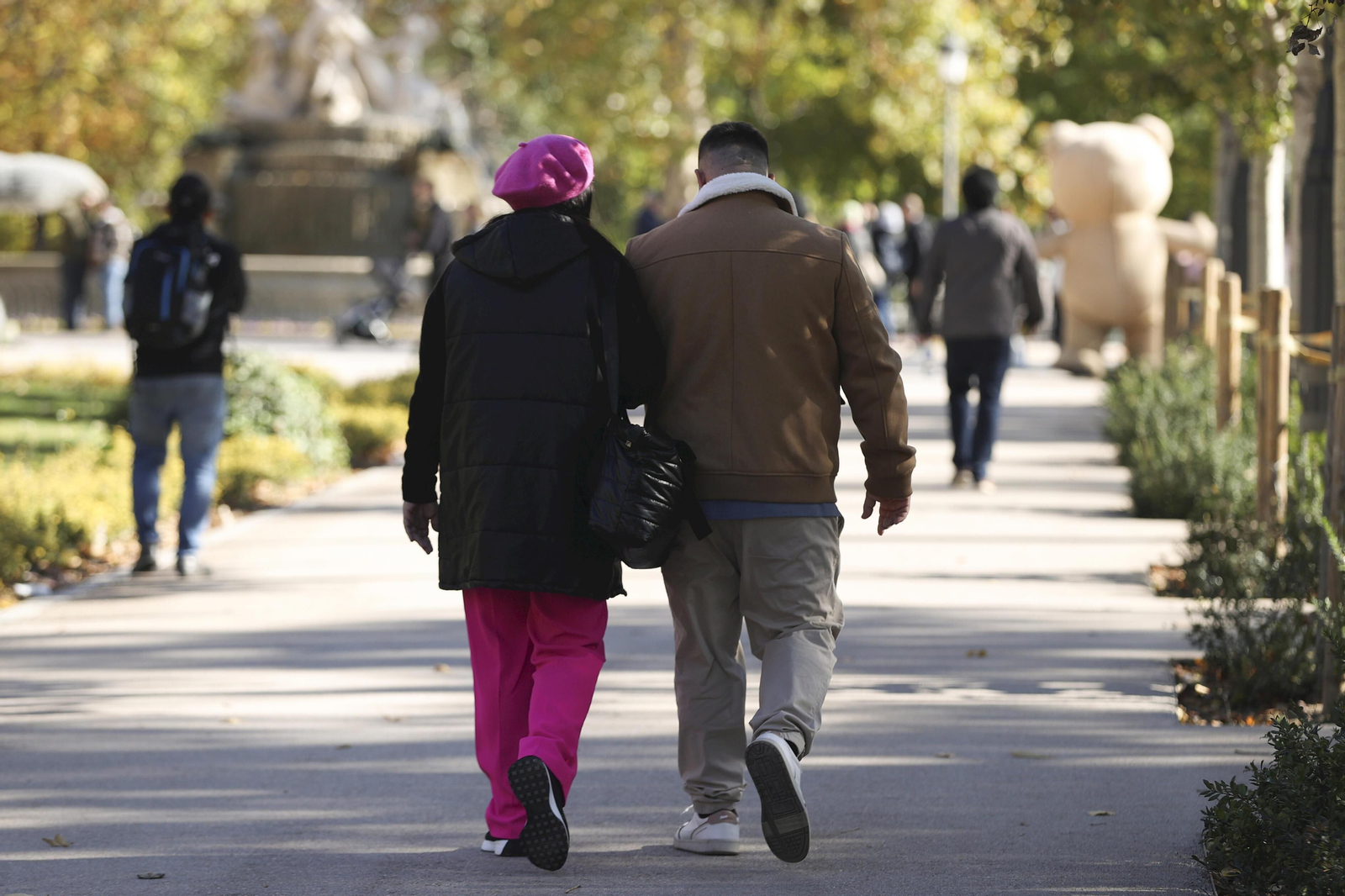 Dos personas abrigadas caminando por un paseo peatonal