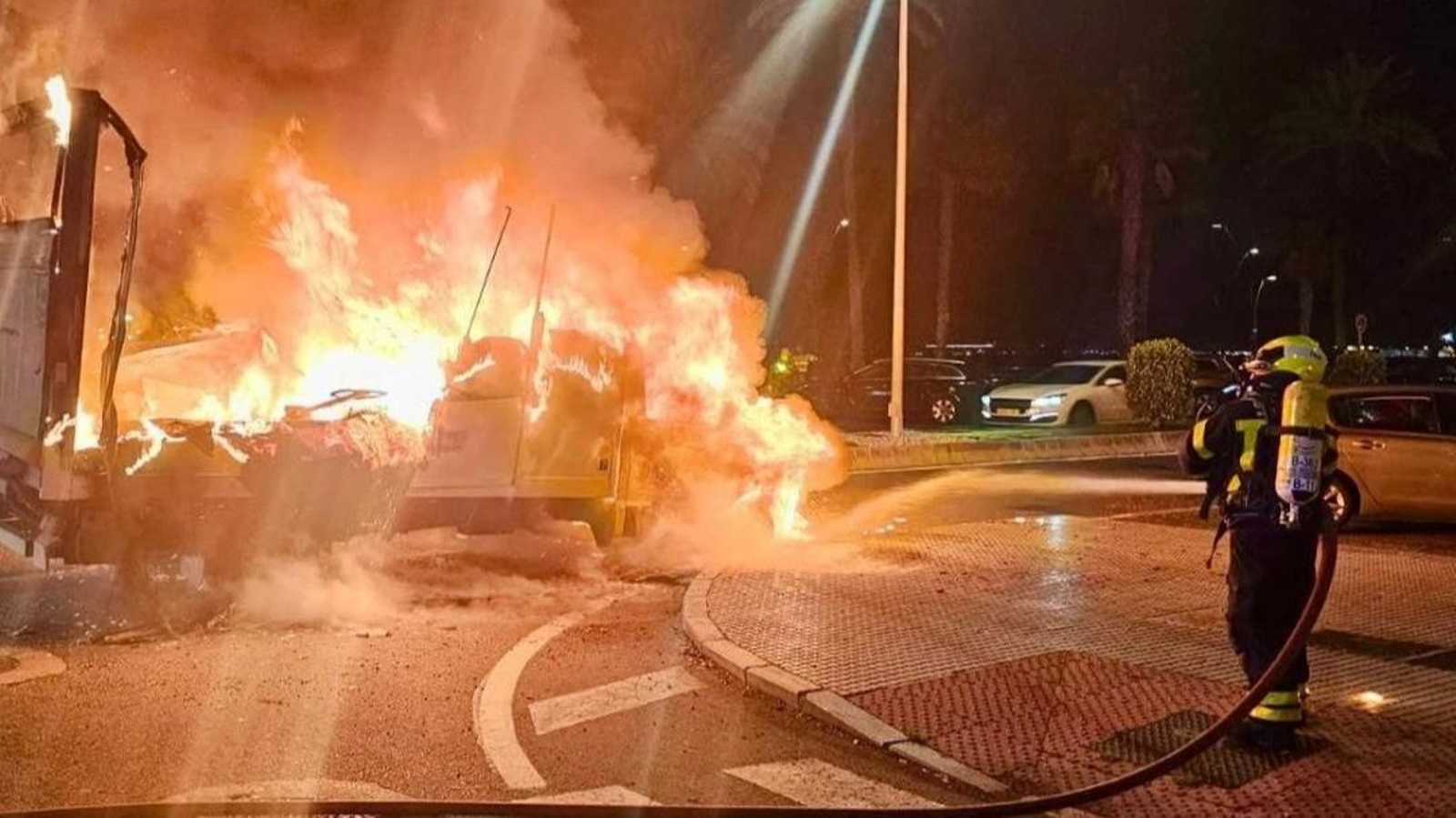 Un bombero apaga el incendio de un camión en la avenida de la Bahía, en Cádiz.