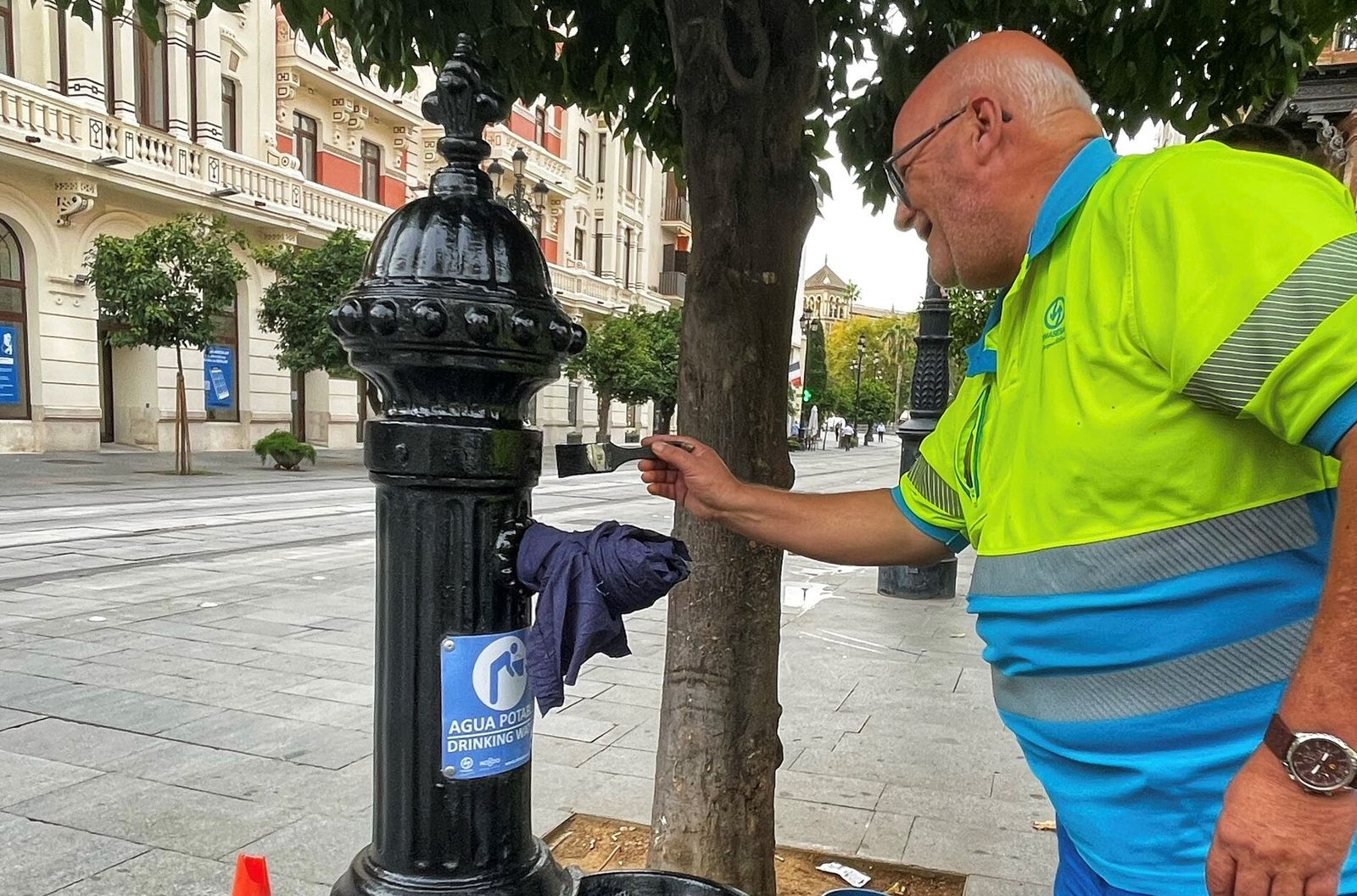 Un operario de Emasesa limpia una fuente de agua potable.