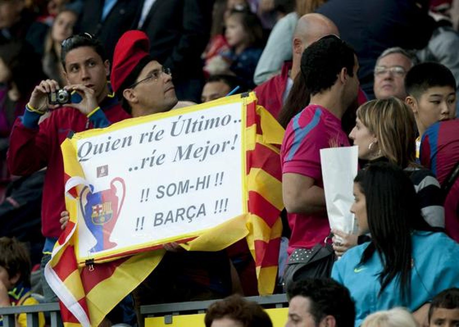 Un aficionado azulgrana, con una pancarta dedicada al Madrid en la grada. / EFE