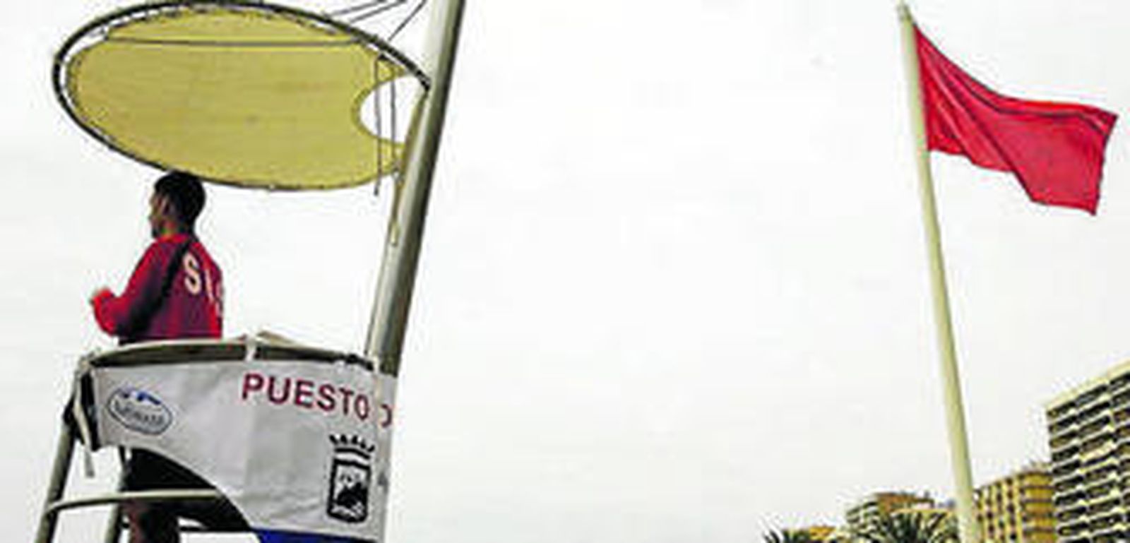 Un socorrista, ayer, junto a una bandera roja.