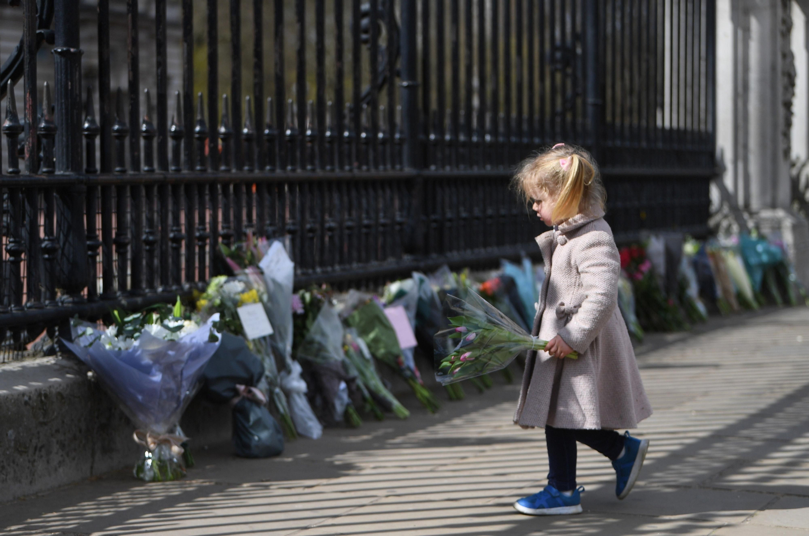 Una pequeña pone flores ante el Palacio de Buckingham.