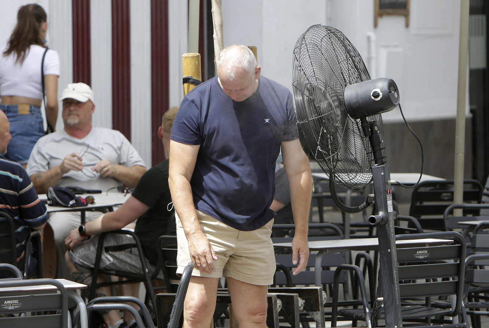 Un hombre se refresca delante de un ventilador en la terraza de un bar en Sevilla.