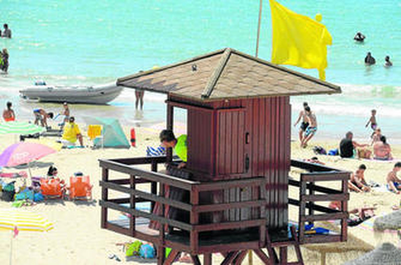 Un vigilante supervisa a los bañistas en una playa de Cádiz.