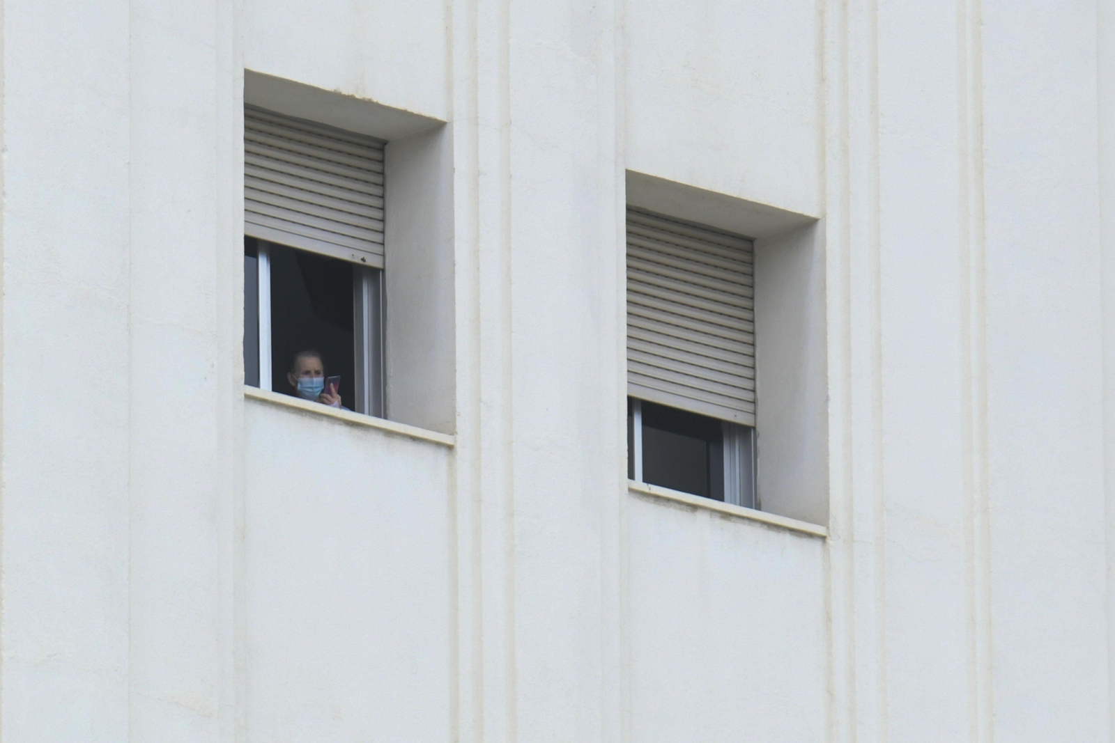 Una mujer mira su teléfono móvil desde su habitación en el Virgen de las Nieves