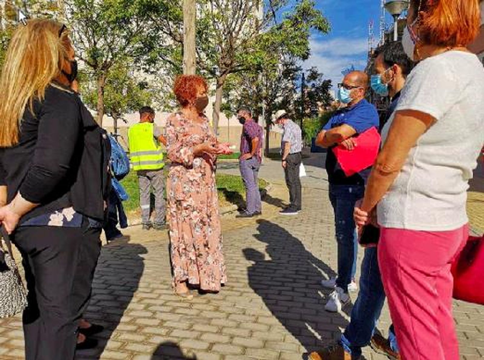 Adela conversa con vecinos mientras un operario trabaja en una zona ajardinada.