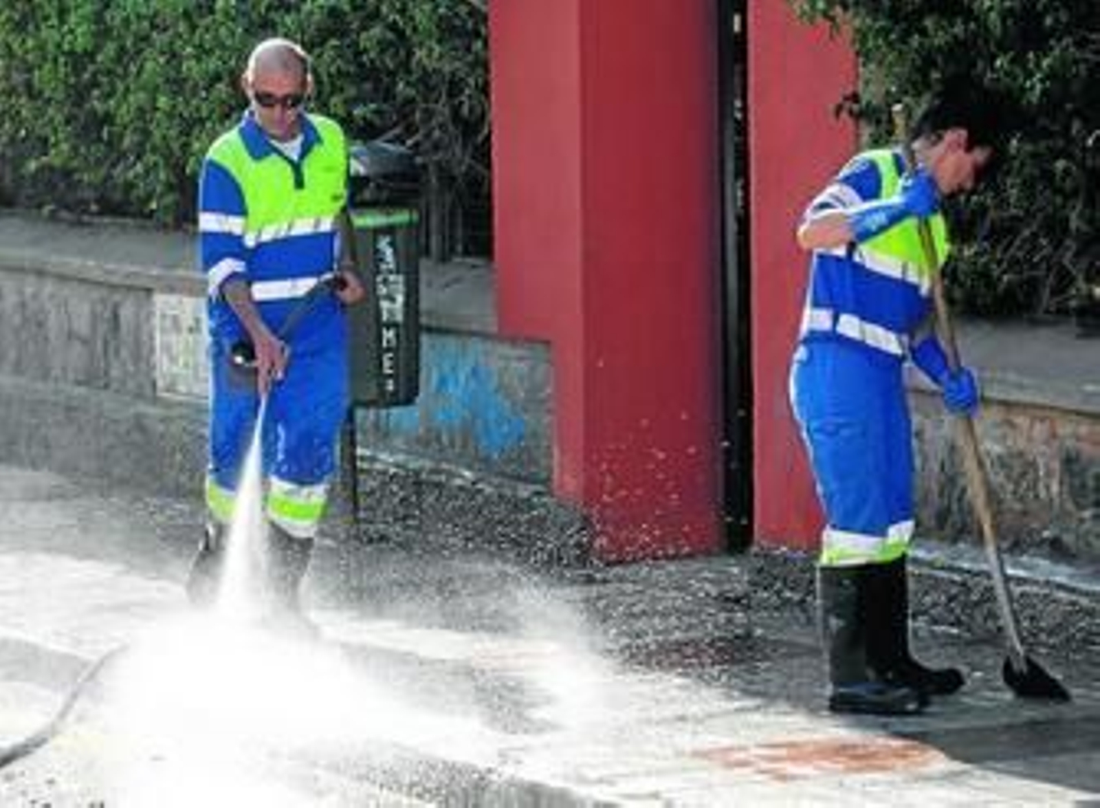 Dos operarios de Limasa limpian una acera de la zona de Carranque de la capital.