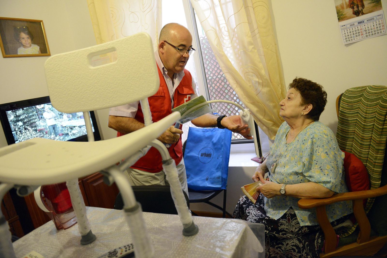 Un voluntario de Cruz Roja atendiendo a una persona mayor.