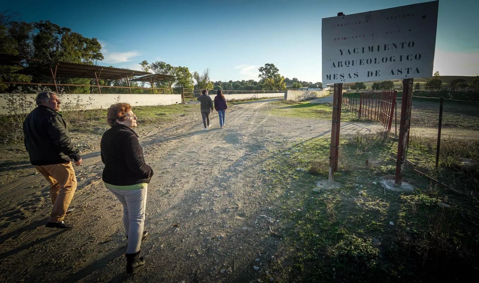 Vecinos de Mesas de Asta, ante el cartel de entrada al yacimiento.