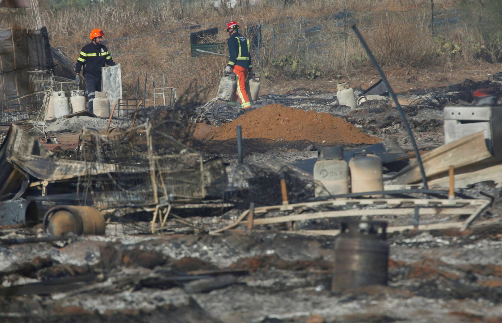 Los bomberos trabajan la mañana siguiente del gran incendio del 15 de octubre en un asentamiento de Lepe que arrasó 4 hectáreas de terreno.