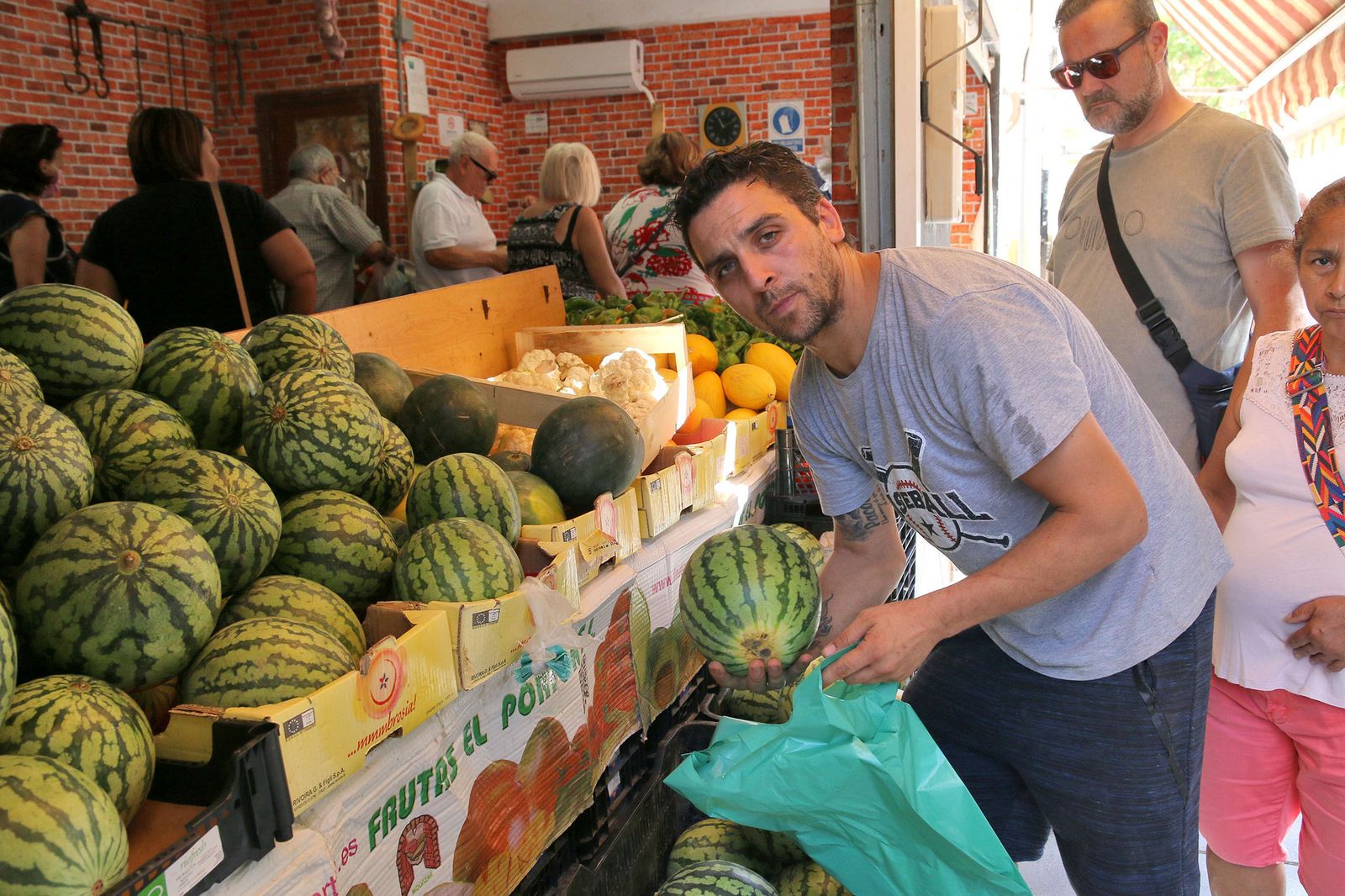 Paco selecciona un ejemplar de sandía delante de su frutería, sita junto al Mercado de Los Ángeles.