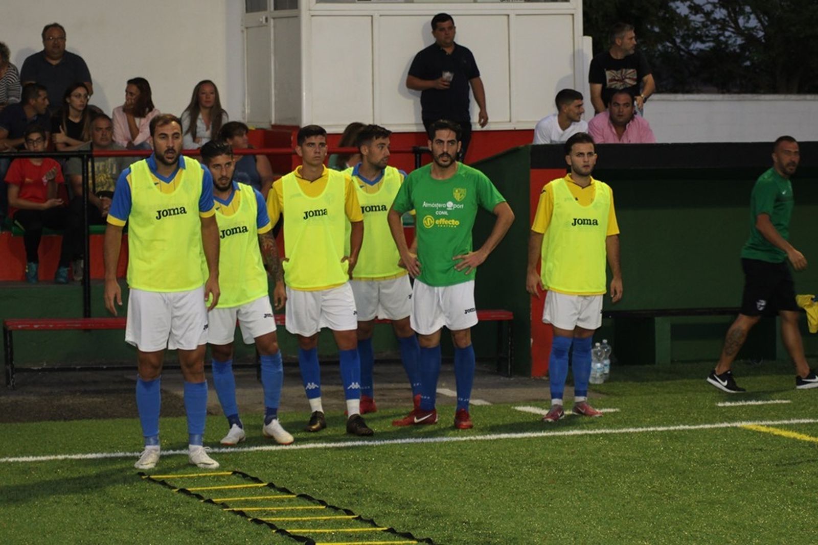Jugadores del Conil siguen desde la banda un anterior amistoso de su equipo.