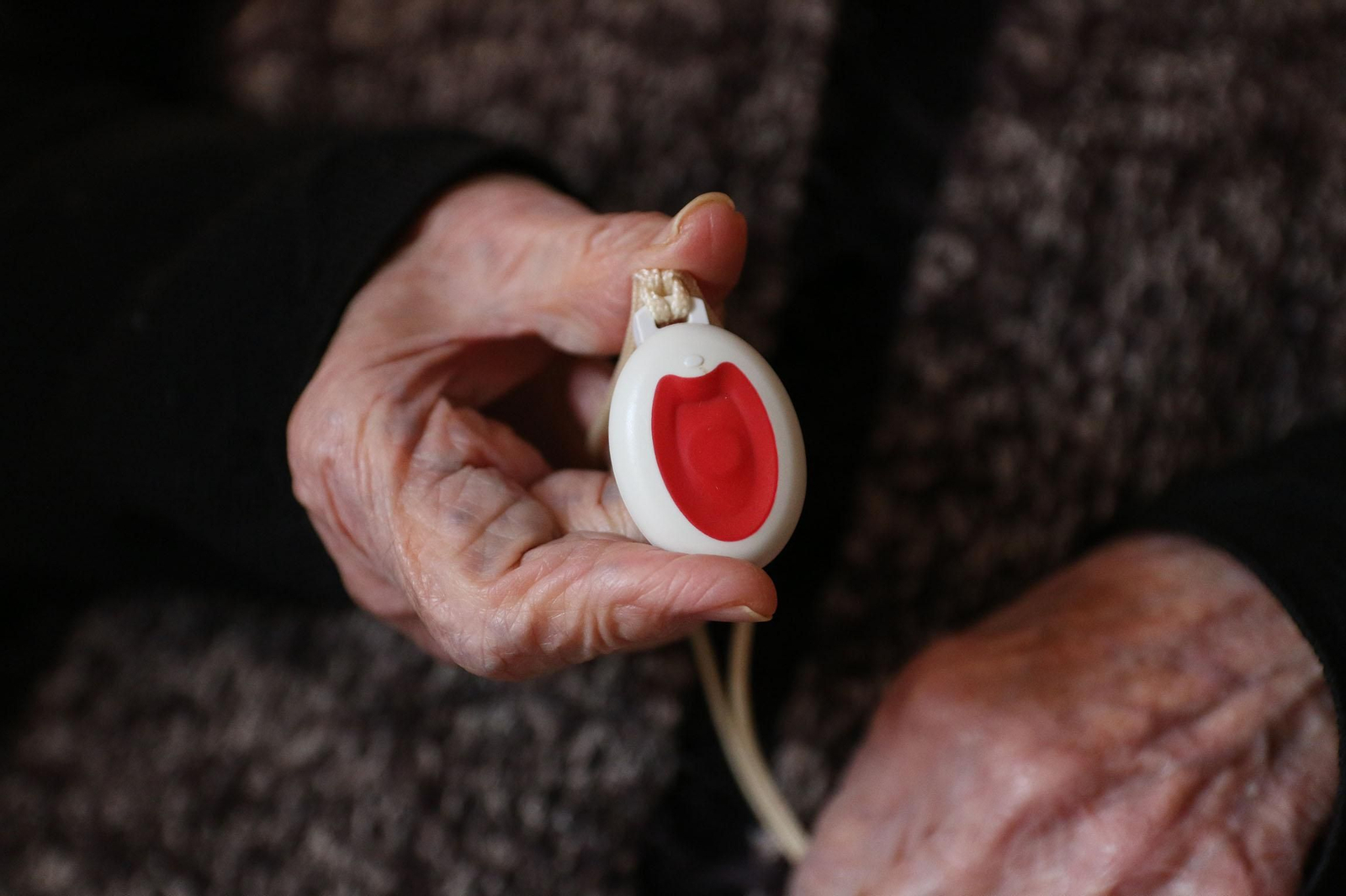 Una persona mayor con el botón de la teleasistencia