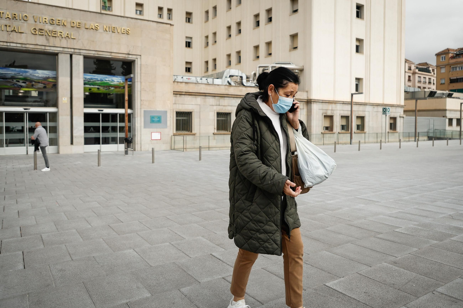 Una mujer con mascarilla caminando frente a las puertas del Hospital Virgen de las Nieves