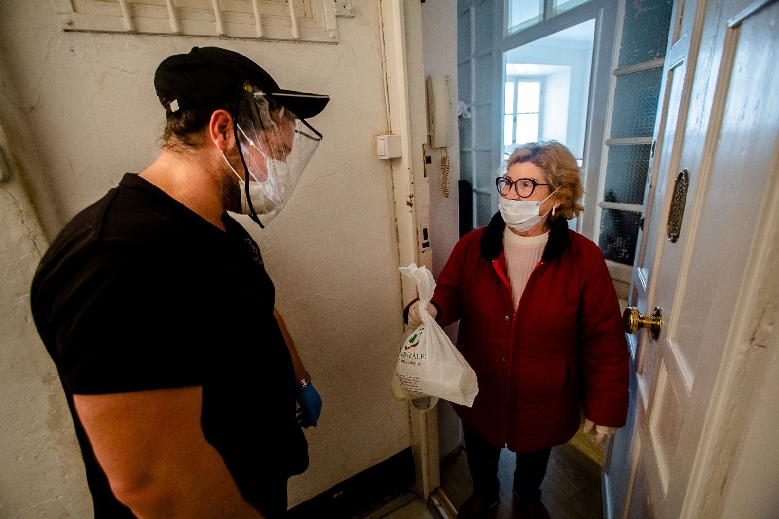 Dolores González del Río recibe los menús por parte del repartidor de la empresa Hermanos González.