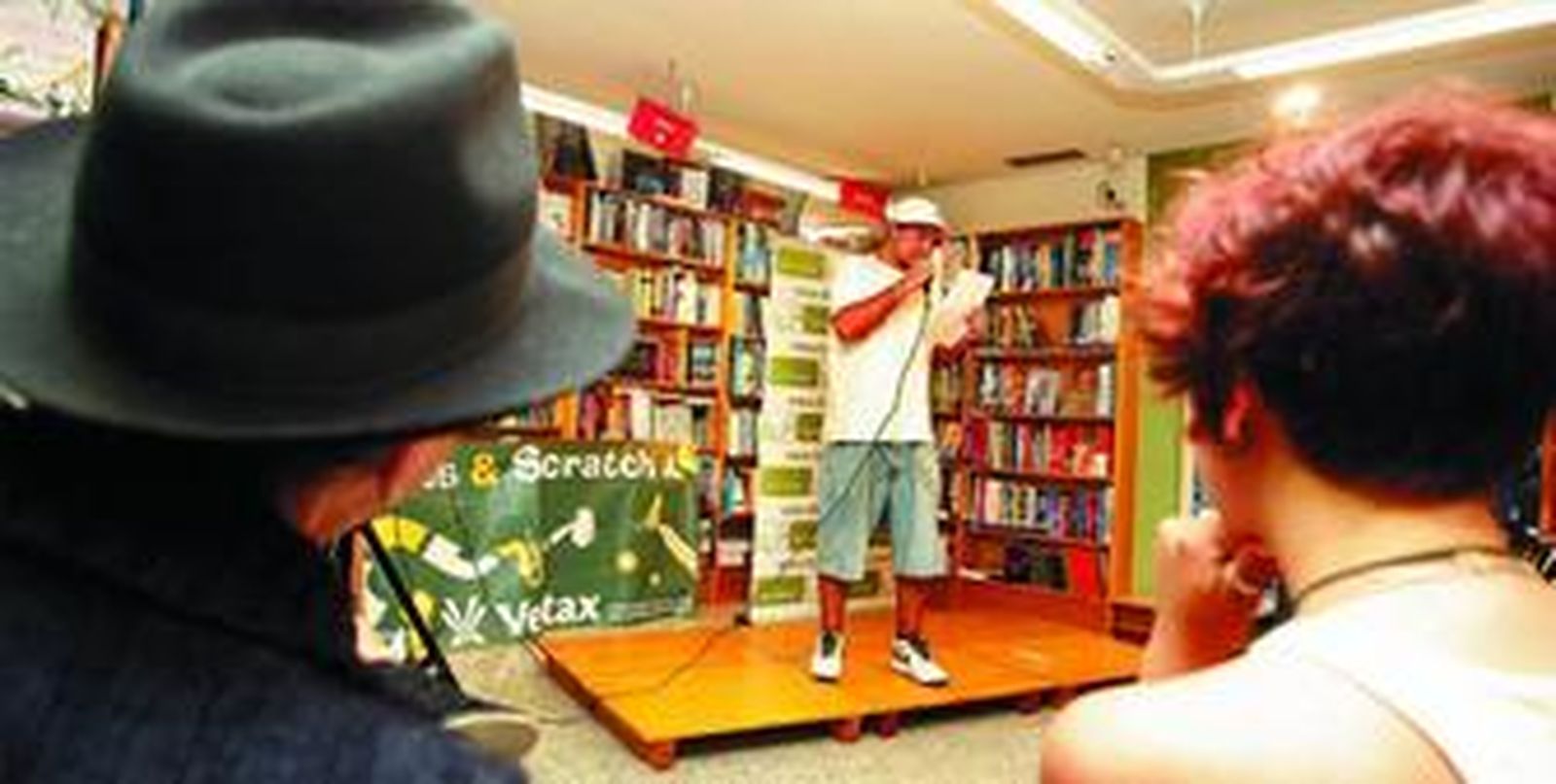 De espaldas, Francisco Cumpián escucha a uno de los jóvenes participantes en el 'Slam poetry' que se celebró ayer en la librería Luces.