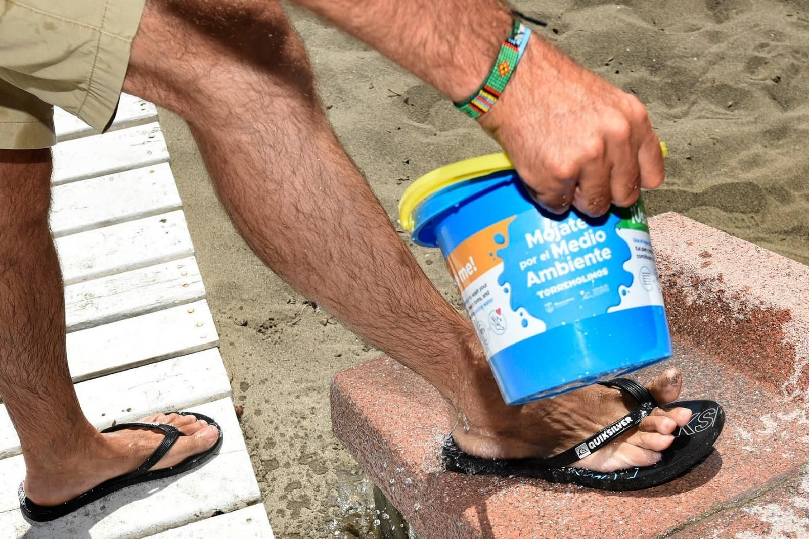 Un hombre enjuagándose los pies con agua de la playa. Un hombre enjuagándose los pies con agua de la playa.