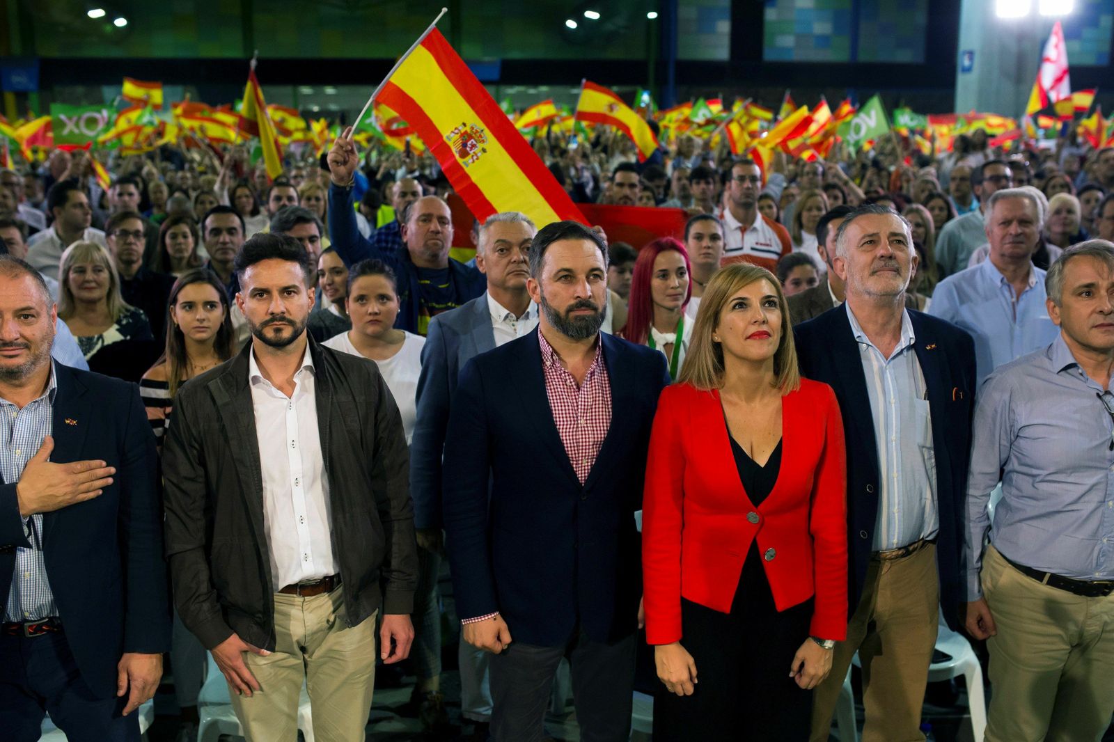 Santiago Abascal junto a Patricia Rueda y José Enrique Lara escuchan el himno de España durante el mitin en el Palacio de Ferias de Málaga.
