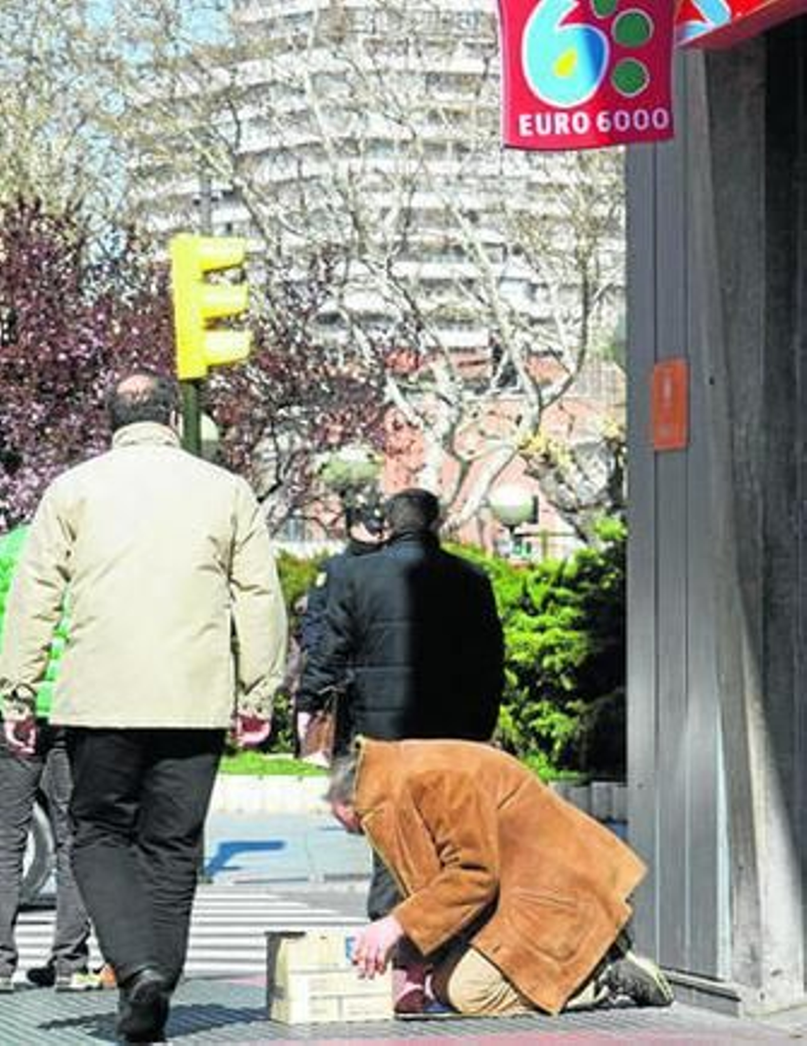 Un hombre pide limosna en la puerta de una sucursal bancaria en Zaragoza.