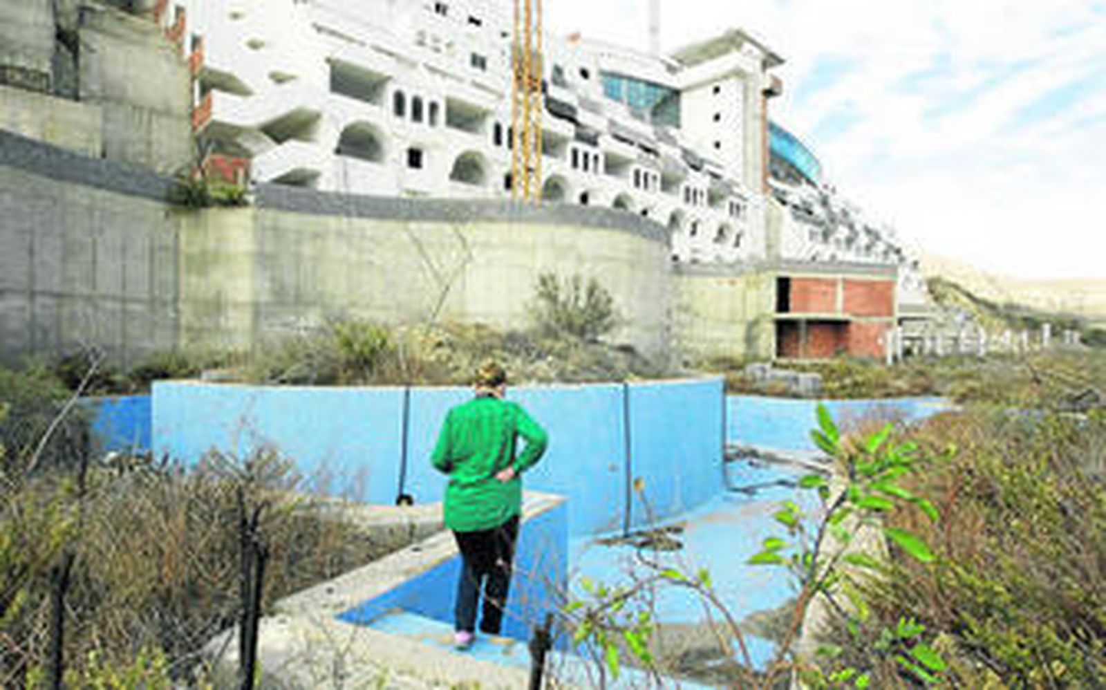 Una vecina del municipio contempla las instalaciones abandonadas desde que el hotel fuera paralizado por orden del juez hace ocho años.