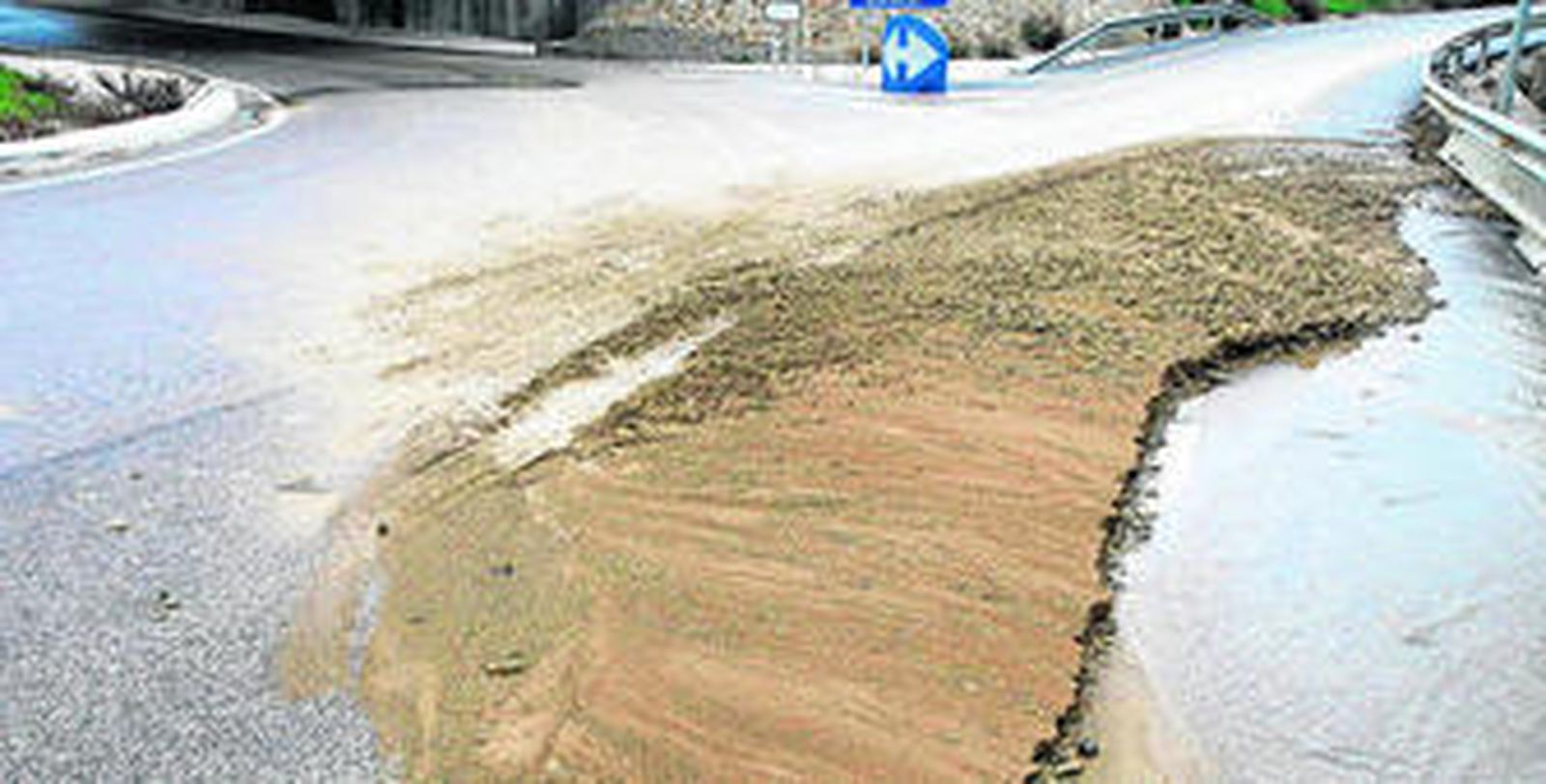 Imagen de parte del muro de cerramiento del Higuerón cedido y de la tierra en el asfalto.