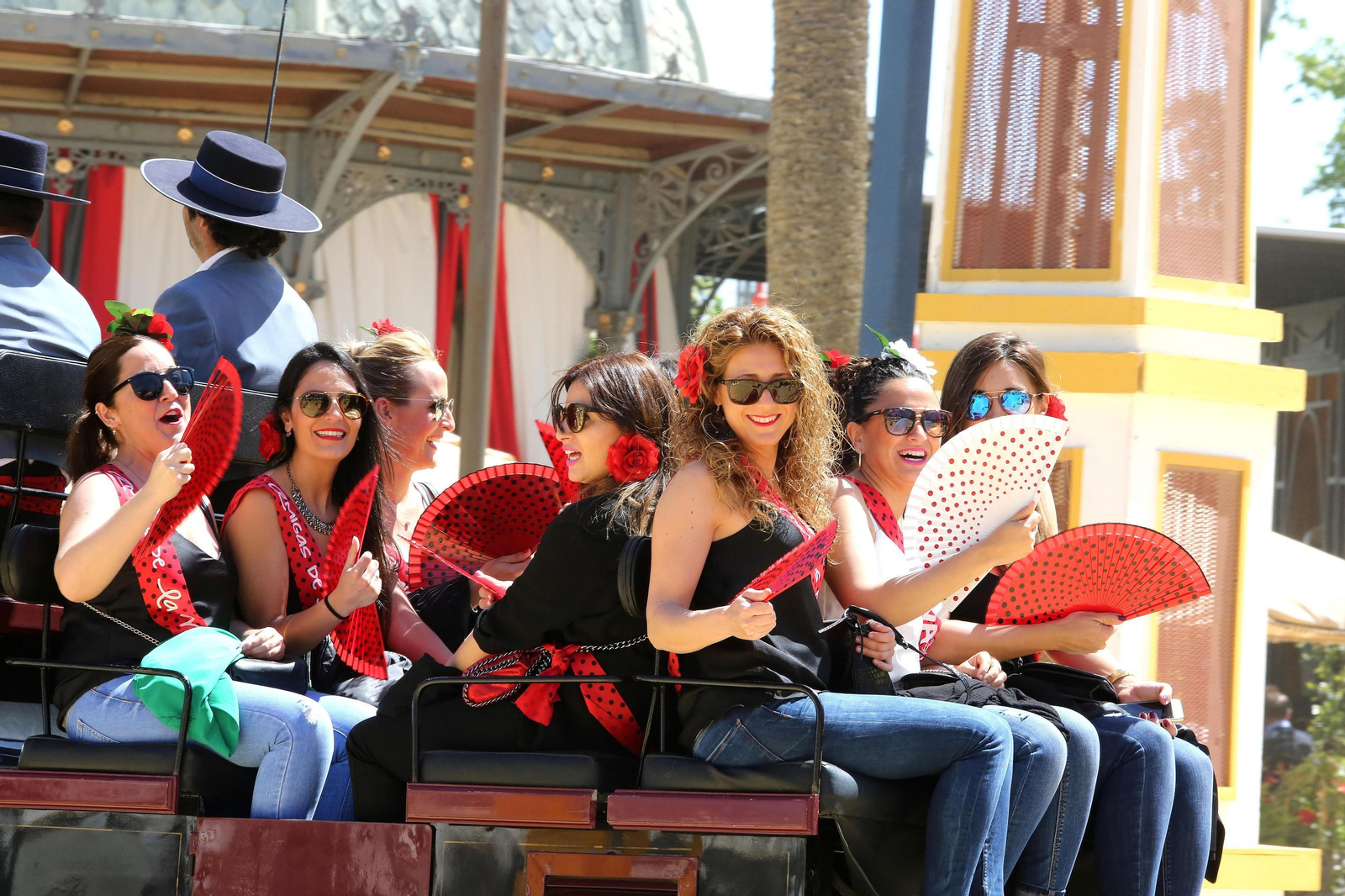 Unas chicas saludan desde un coche de caballos.