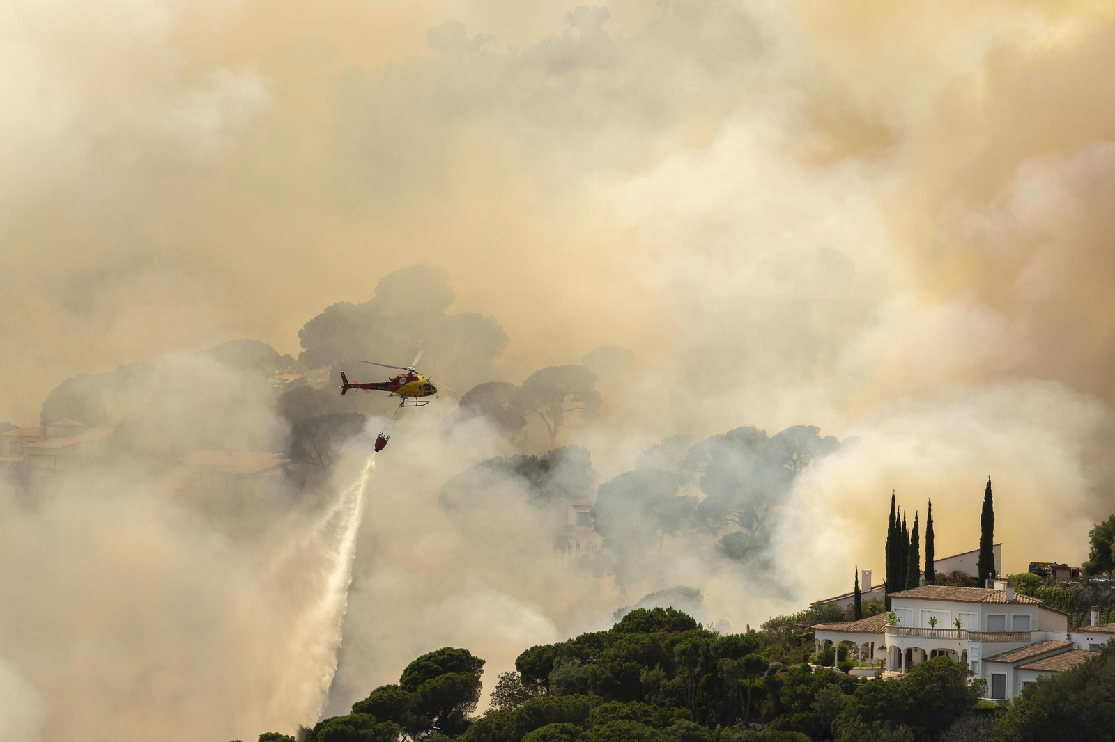 Un helicóptero trata de sofocar las llamas de un incendio en Santa Cristina d'Aro, en Girona