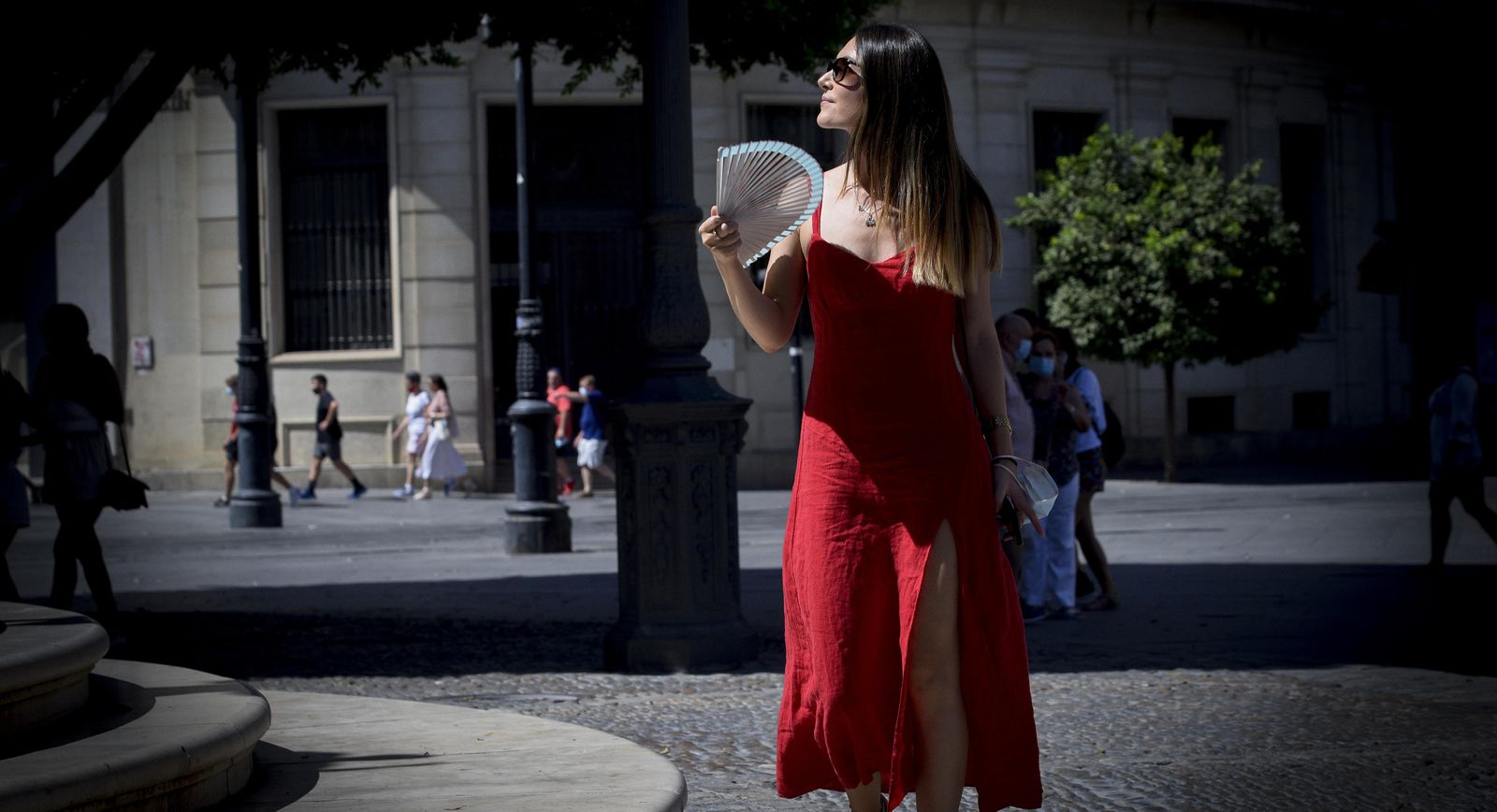 Una mujer se abanica al pasear por la Avenida de la Constitución.
