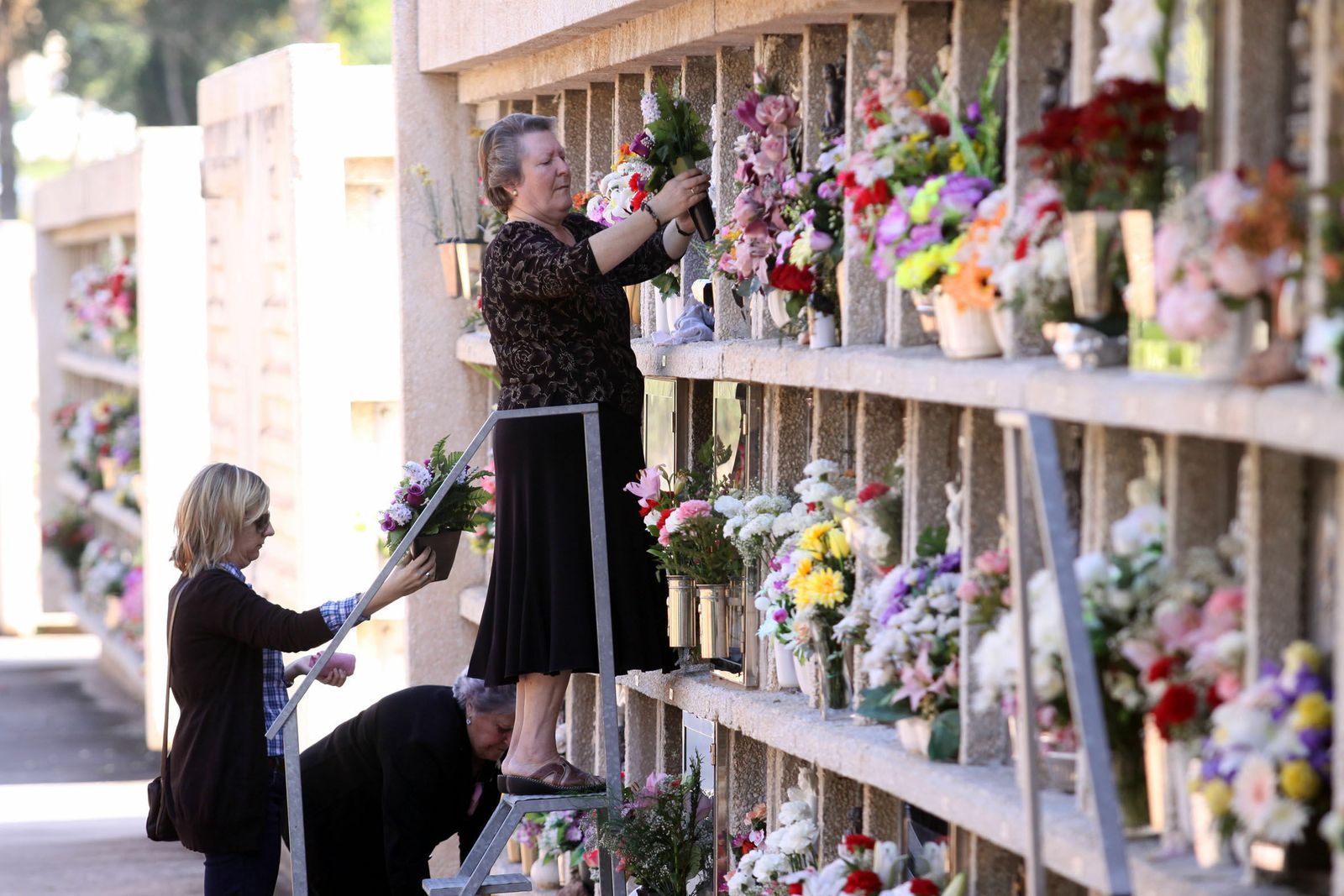 Varias mujeres ponen flores en un cementerio.