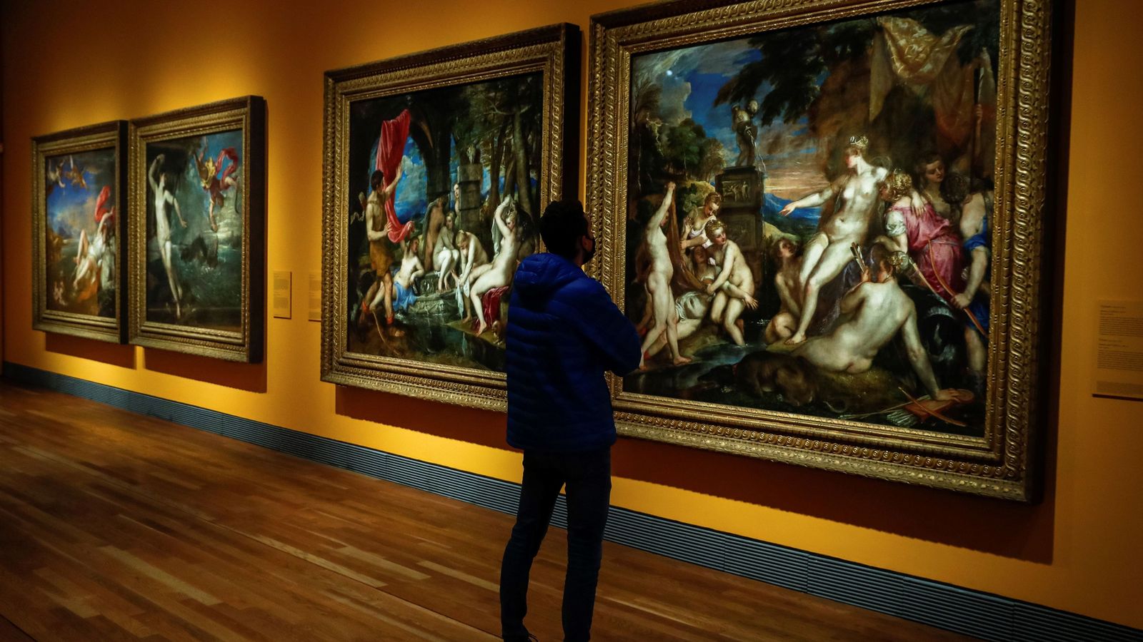 Un hombre observa la obra "Diana y Calisto" (dcha), (1556-1559), de Tiziano.