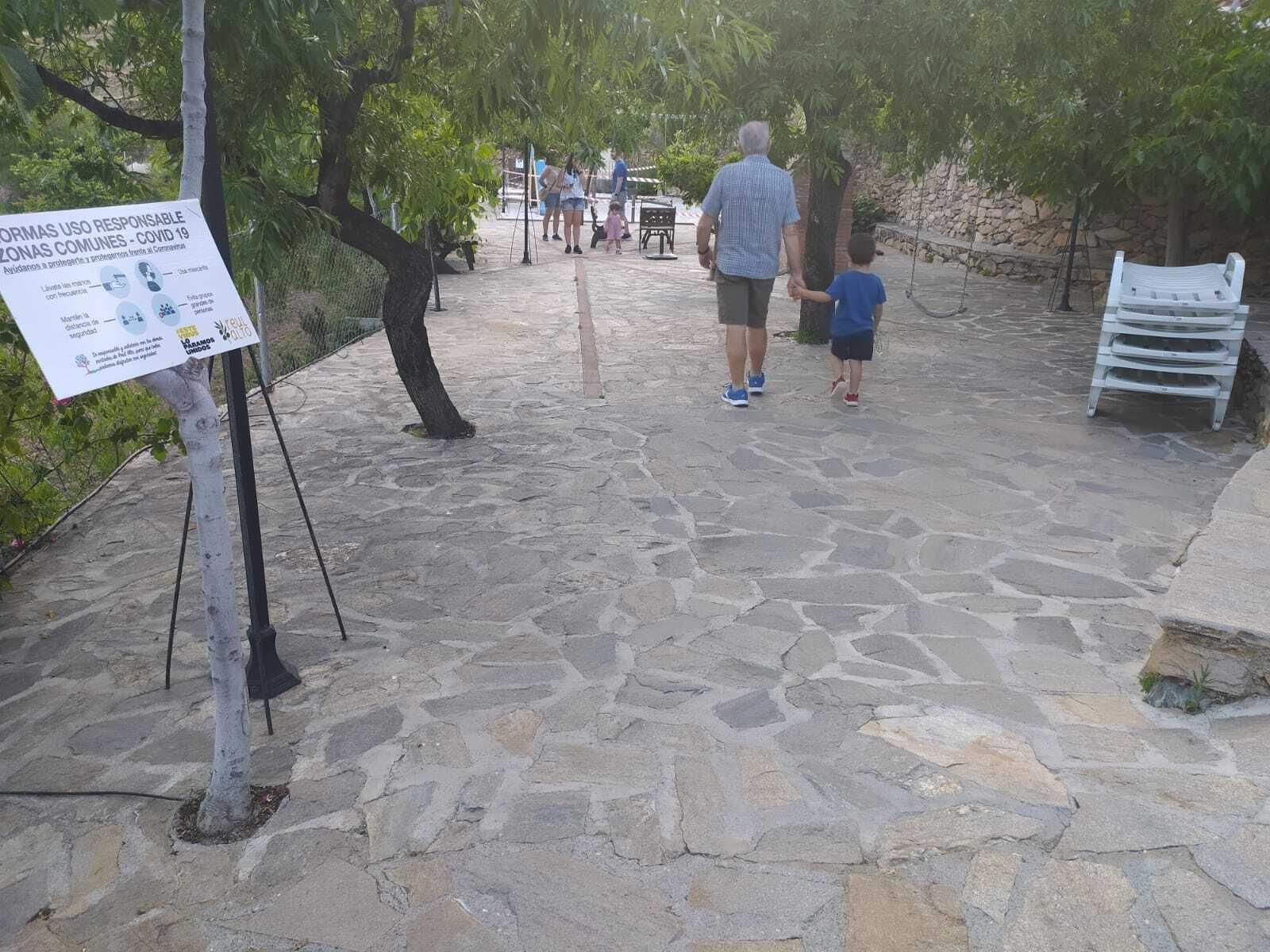 Sobrino y nieto pasean por el complejo de Reul Alto, en Laroya, con un cartel de seguridad ante el coronavirus.