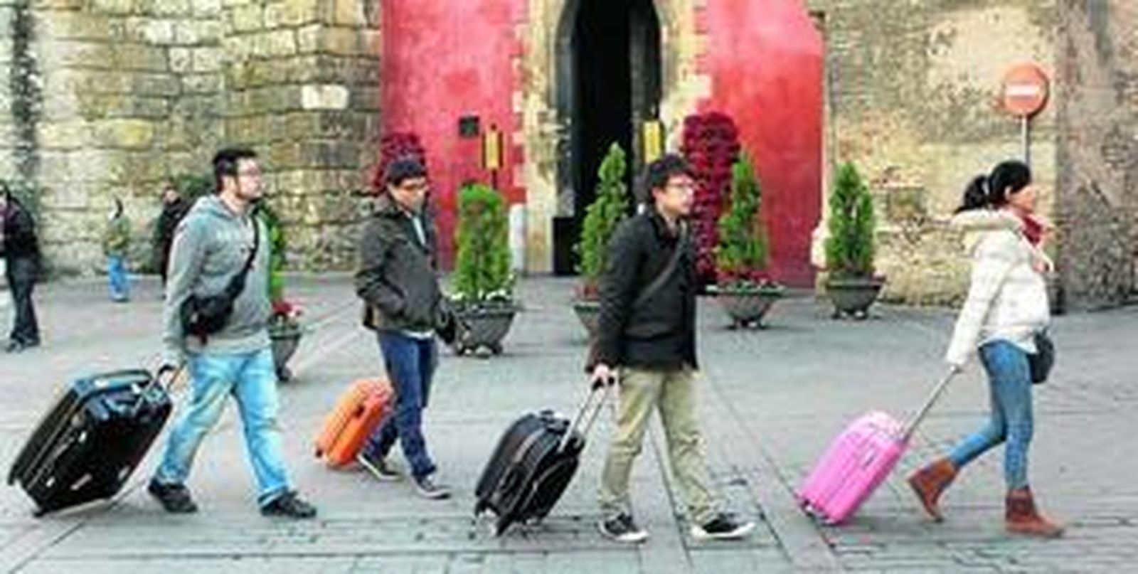 Un grupo de turistas, maleta en mano, pasa por delante de la Puerta del León del Real Alcázar de Sevilla.