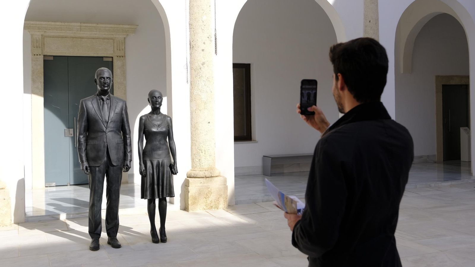 Un visitante fotografía las esculturas de los reyes de España, obra de Antonio López.
