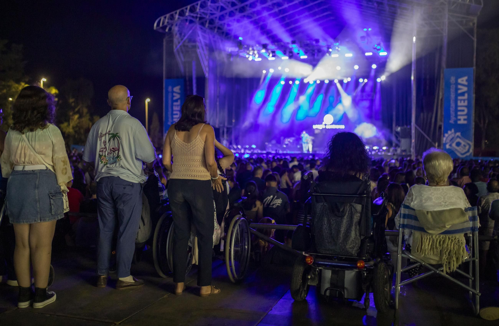 Un grupo de personas con movilidad reducida disfruta de la primera noche de conciertos de las Fiestas Colombinas 2024.
