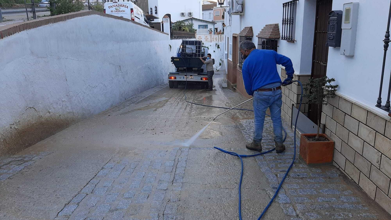 Una persona retirando lodo de una calle Una persona retirando lodo de una calle