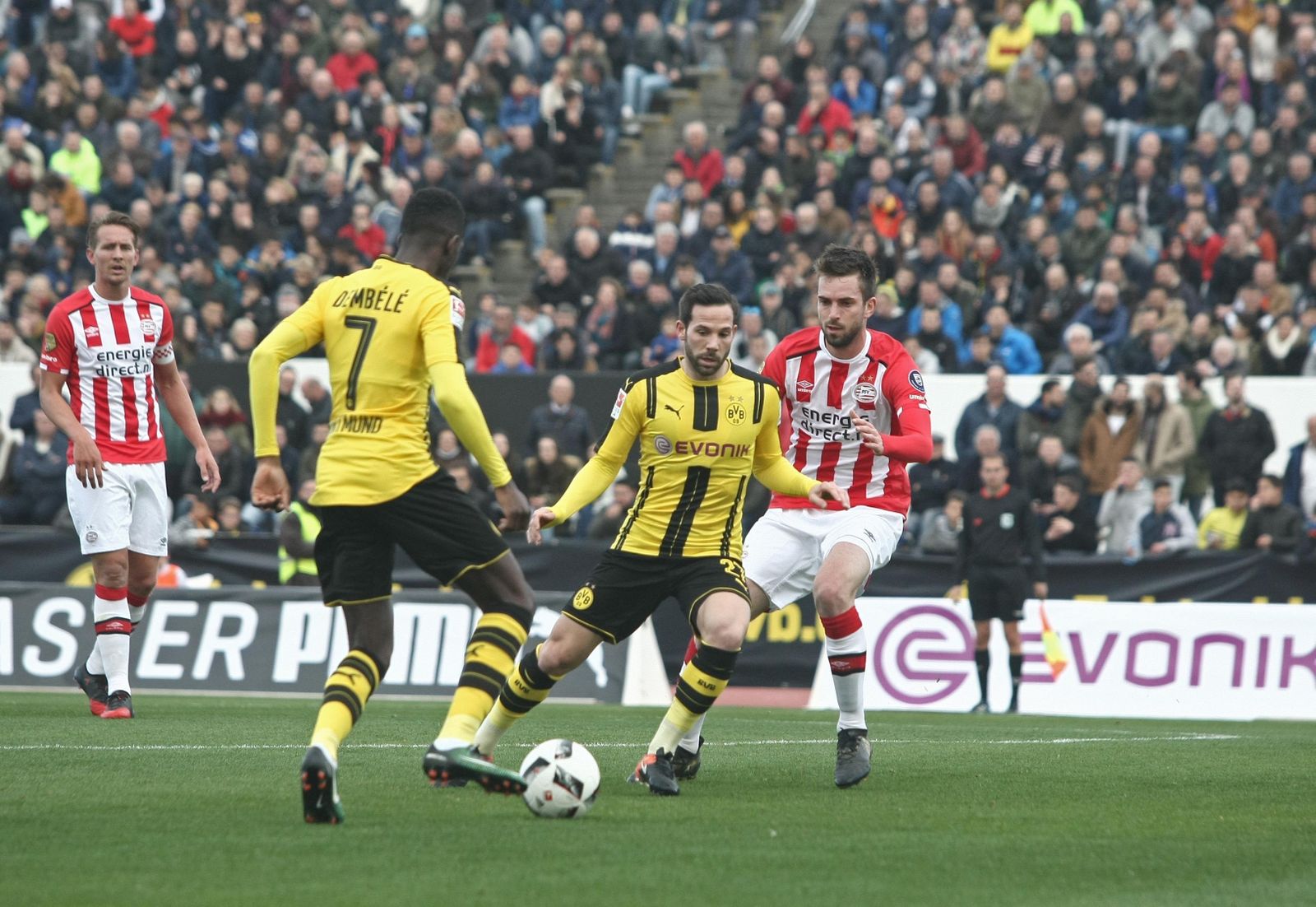 1. El 'germano-linense' Gonzalo Castro, en el centro, espera el pase de su compañero Dembélé. 2. El internacional alemán Marco Reus entra en el área tras marchase del colombiano del PSV Santiago Arias. 3. Las gradas del Municipal registraron un gran ambiente. 4. El técnico del cuadro de Eindhoven, el ex azulgrana Cocu.