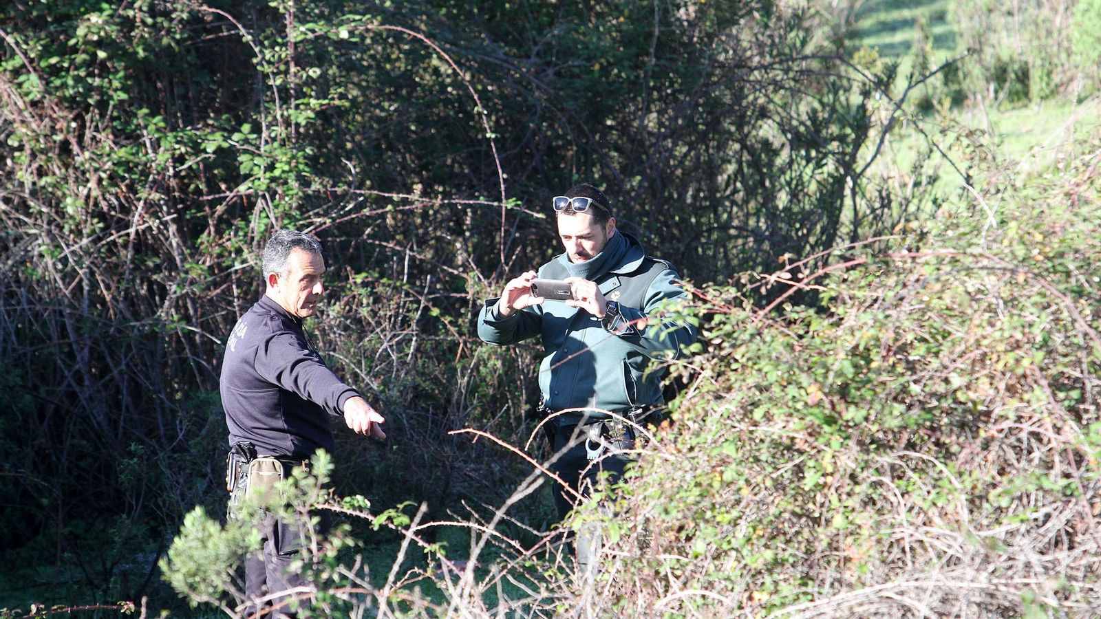 Un agente de la Guardia Civil realiza una fotografía durante el rastreo junto a un policía. Un agente de la Guardia Civil realiza una fotografía durante el rastreo junto a un policía.
