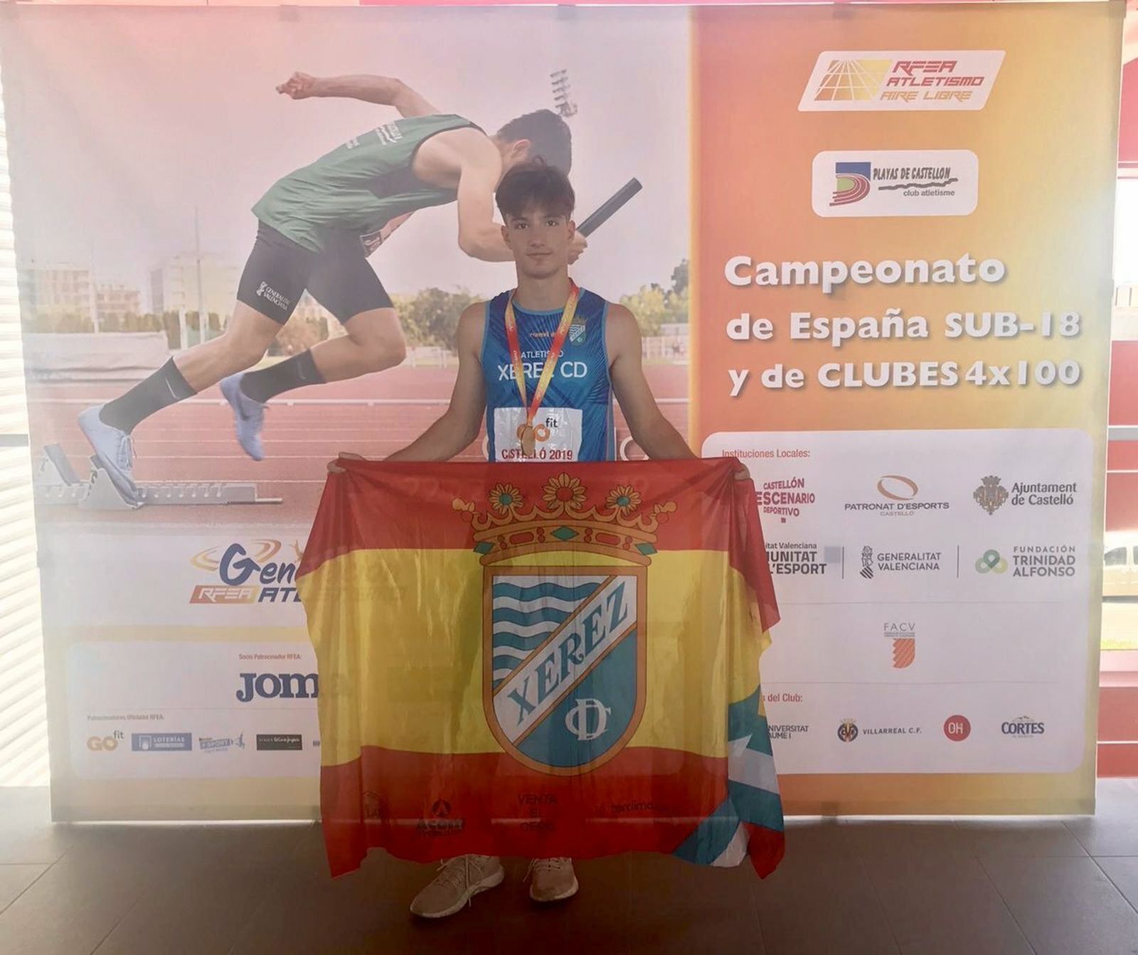 Mario Mena, con la bandera de España y el escudo del Xerez CD tras proclamarse campeón de España Sub-18.