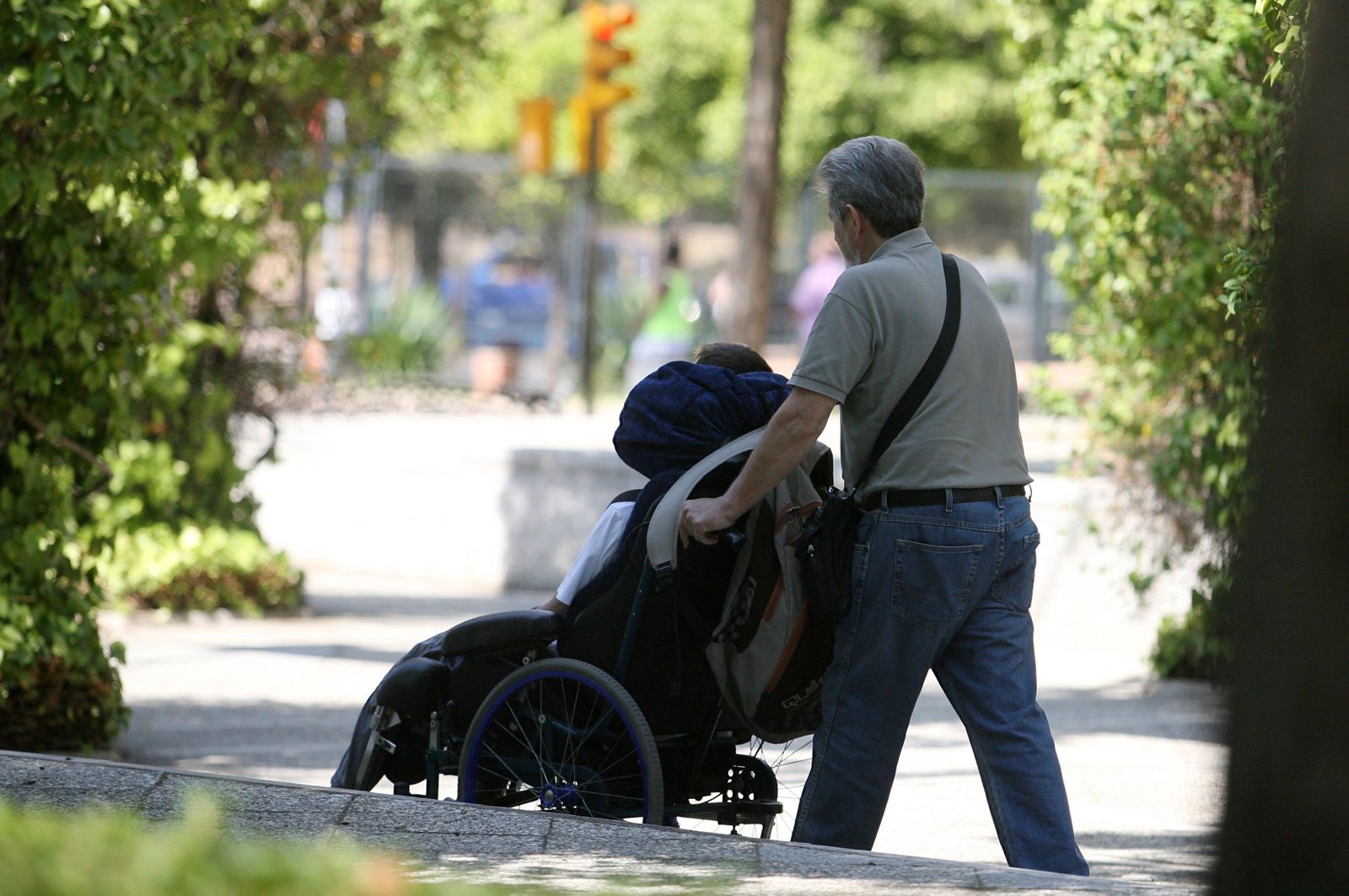 Una persona pasea a un joven en silla de ruedas